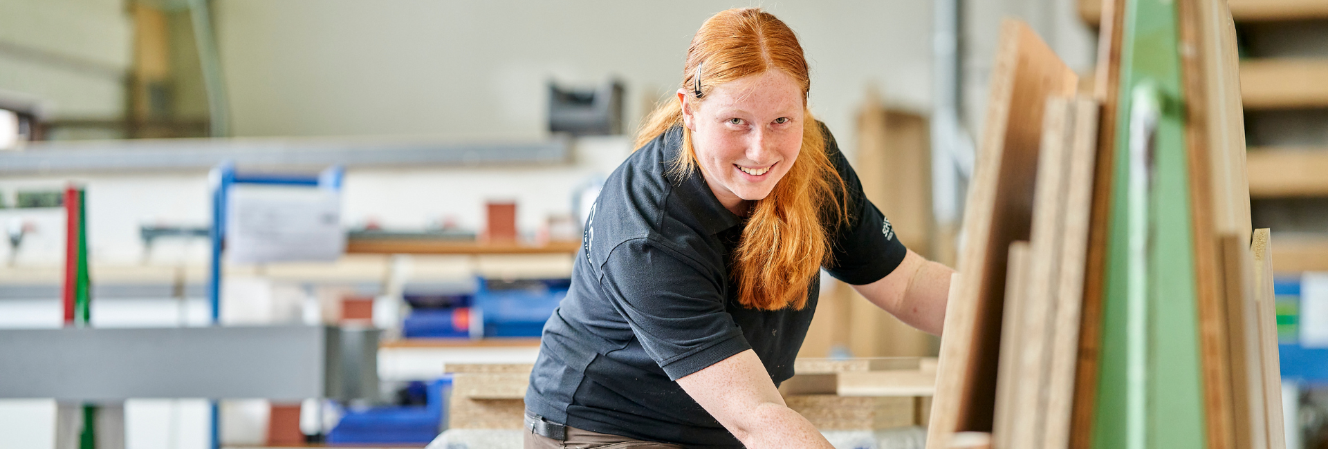 Tischler Azubi in der Produktion bei Schemberg Ladenbau am Arbeiten mit Blick in die Kamera