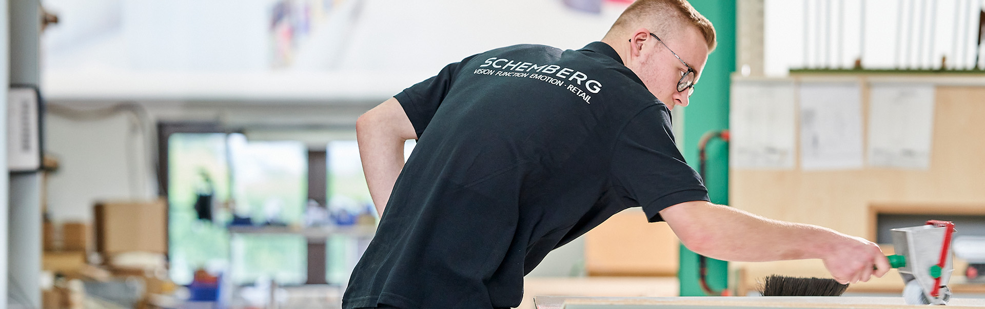 Tischler Azubi in der Produktion bei Schemberg Ladenbau am Verleimen